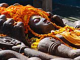 Kathmandu Valley 1 Budhanikantha 3 Sleeping Vishnu Head Close Up Budhanilkantha Narayan (Sleeping Vishnu) lies peacefully on the coils of the multi-headed snake Ananta. The snake�s 11 hooded heads rise protectively around Narayan�s head. Vishnu�s four hands hold the four symbols of Vishnu: chakra disk(representing the mind), a conch shell (the four elements), a mace (primeval knowledge), and a lotus seed (the moving universe).